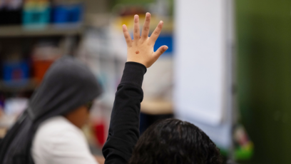 1st Grader raises hand to ask a question during class