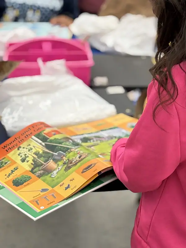 ROI of Reading Interventions — Proving Impact in Student Outcomes & District Budgets 4 1st Grade student Reading open book on a table in a classroom