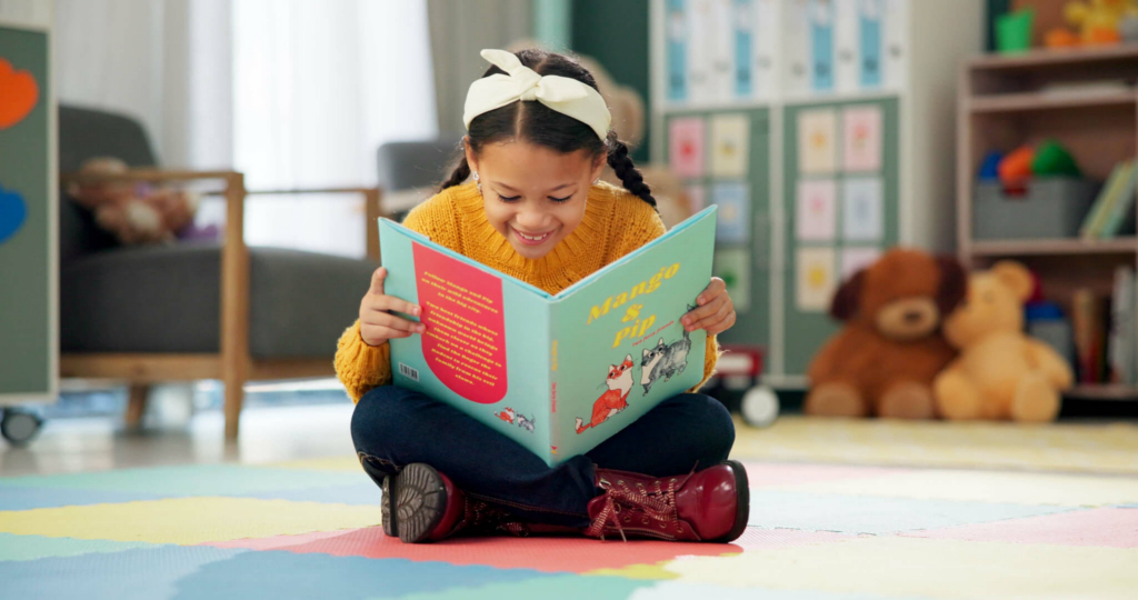 A smiling high-dosage reading tutor looks at a screen