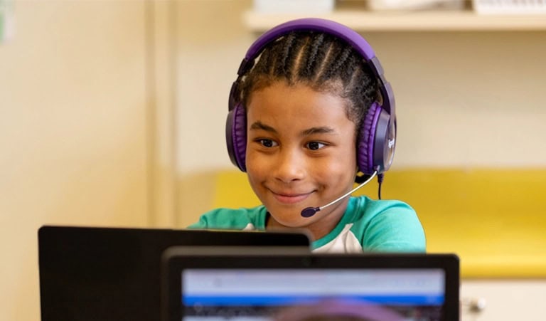 students in a classroom work with their high-dosage tutors virtually via computers