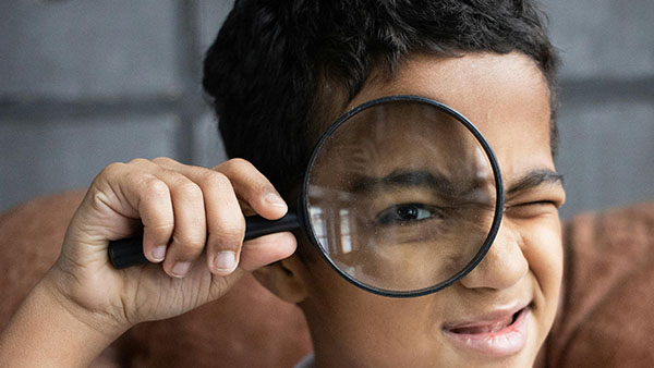 a boy uses a magnifying glass to show off his eagle eye