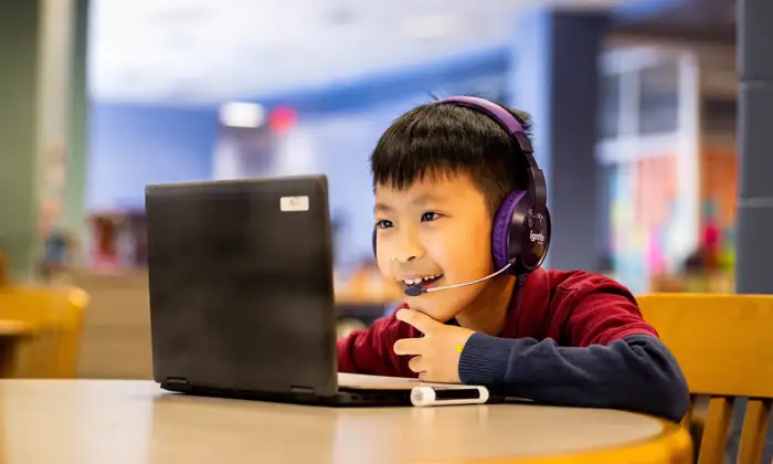 A student holds her tablet and gives a thumbs up to her virtual tutor