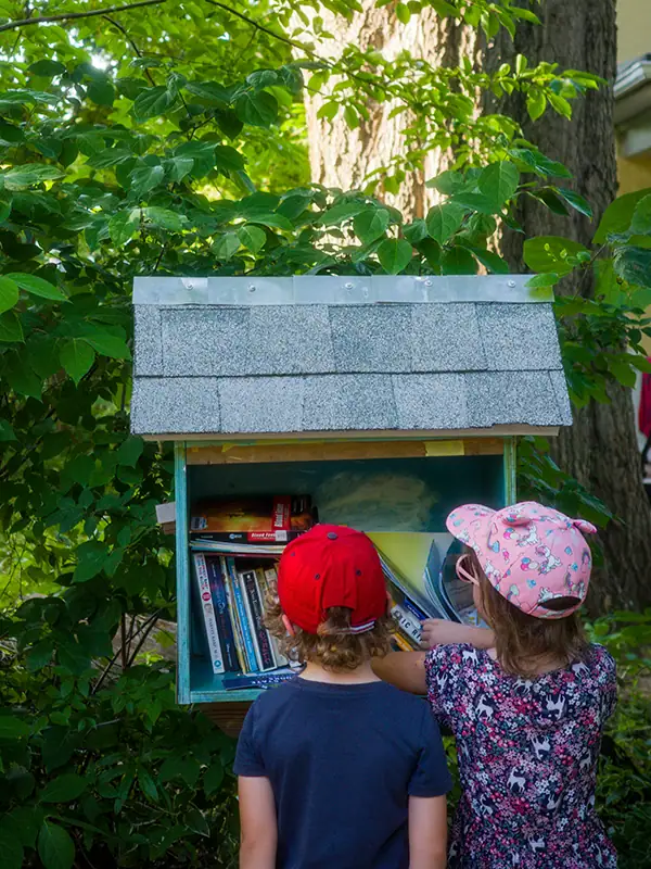 How to Boost Family Engagement in Reading — Tips for Districts & Schools 9 Children place books in a Little Free Library