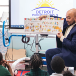 administrator doing a Classroom Read Aloud for kids in Detroit Public Schools holds a book out for the students to look at