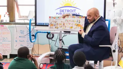 administrator doing a Classroom Read Aloud for kids in Detroit Public Schools holds a book out for the students to look at