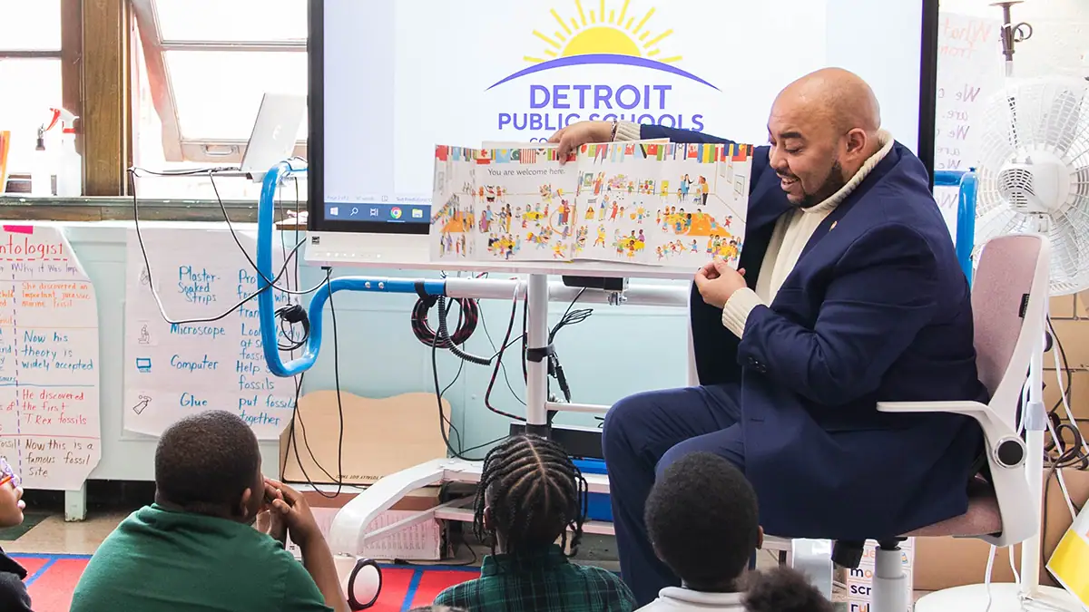 administrator doing a Classroom Read Aloud for kids in Detroit Public Schools holds a book out for the students to look at