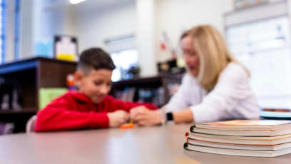 English Language Learner sits with teacher administering assessment in classroom