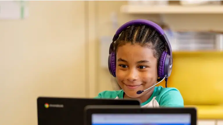 students in a classroom work with their high-dosage tutors virtually via computers
