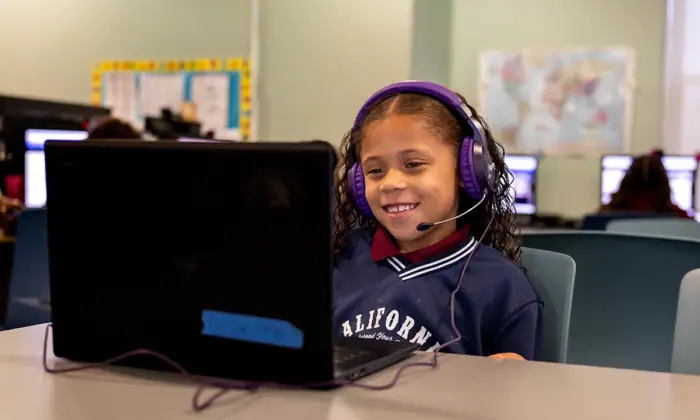 A smiling high-dosage reading tutor looks at a screen