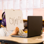 First grader holds up a white board to his computer during a High Dosage Reading Tutoring session in the classroom
