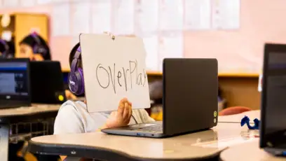 First grader holds up a white board to his computer during a High Dosage Reading Tutoring session in the classroom