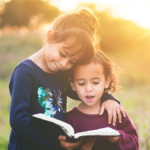 Kids Reading At Home with one child's arm around the other