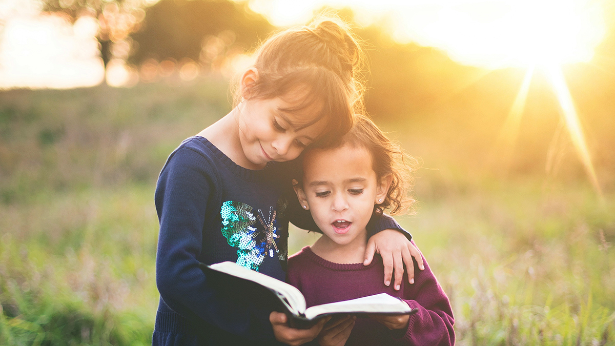 Kids Reading At Home with one child's arm around the other