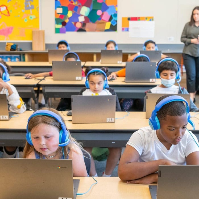 an elementary classroom shows tutoring for students going on with students on laptops with online tutors