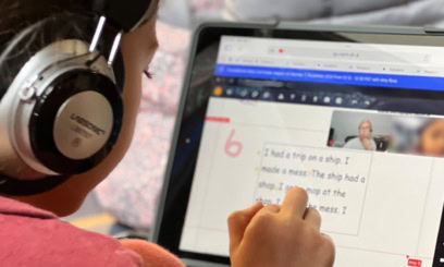 An elementary student works with an online tutor on a laptop