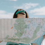 young girl wearing a headband holds a map up in front of her