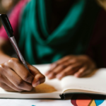 Teacher's hand seen up close holding pen and writing during Professional Development session