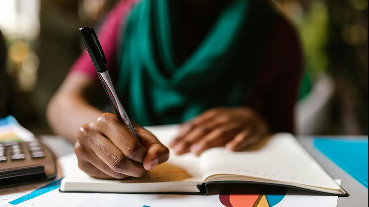 Teacher's hand seen up close holding pen and writing during Professional Development session