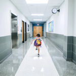 an elementary student walks down an empty school hallway showcasing school attendance issues