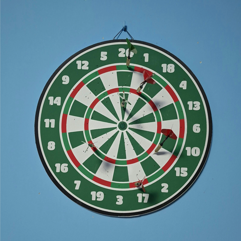Scores on a dart board against a blue wall