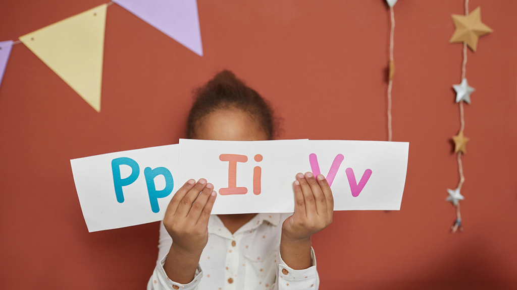 Student Learning Foundational Reading Skills holds up paper with the letters P, I and V