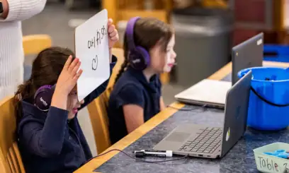 An elementary student works with an online tutor on a laptop