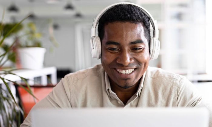 A smiling high-dosage reading tutor looks at a screen