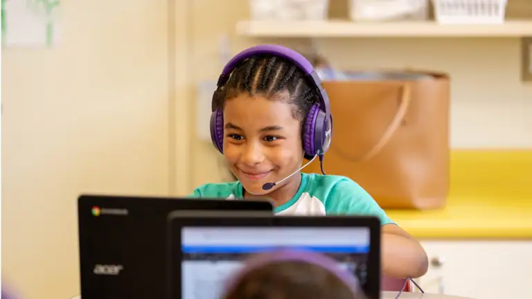 students in a classroom work with their high-dosage tutors virtually via computers
