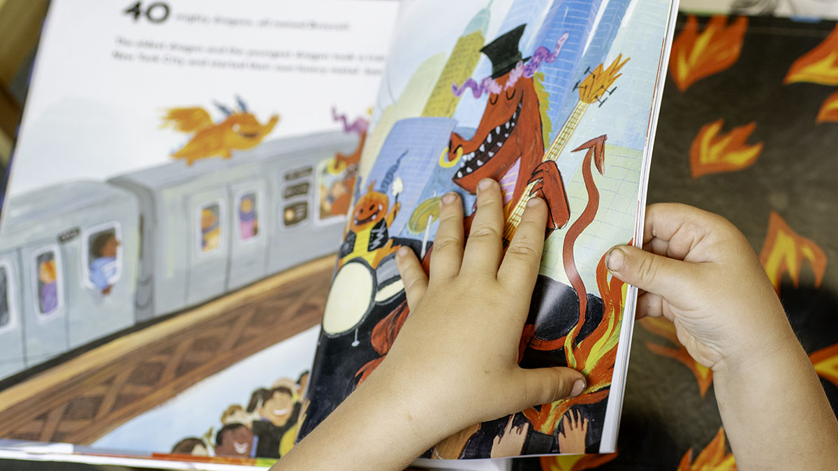 a child's hands turn the pages in a book during a whole language lesson